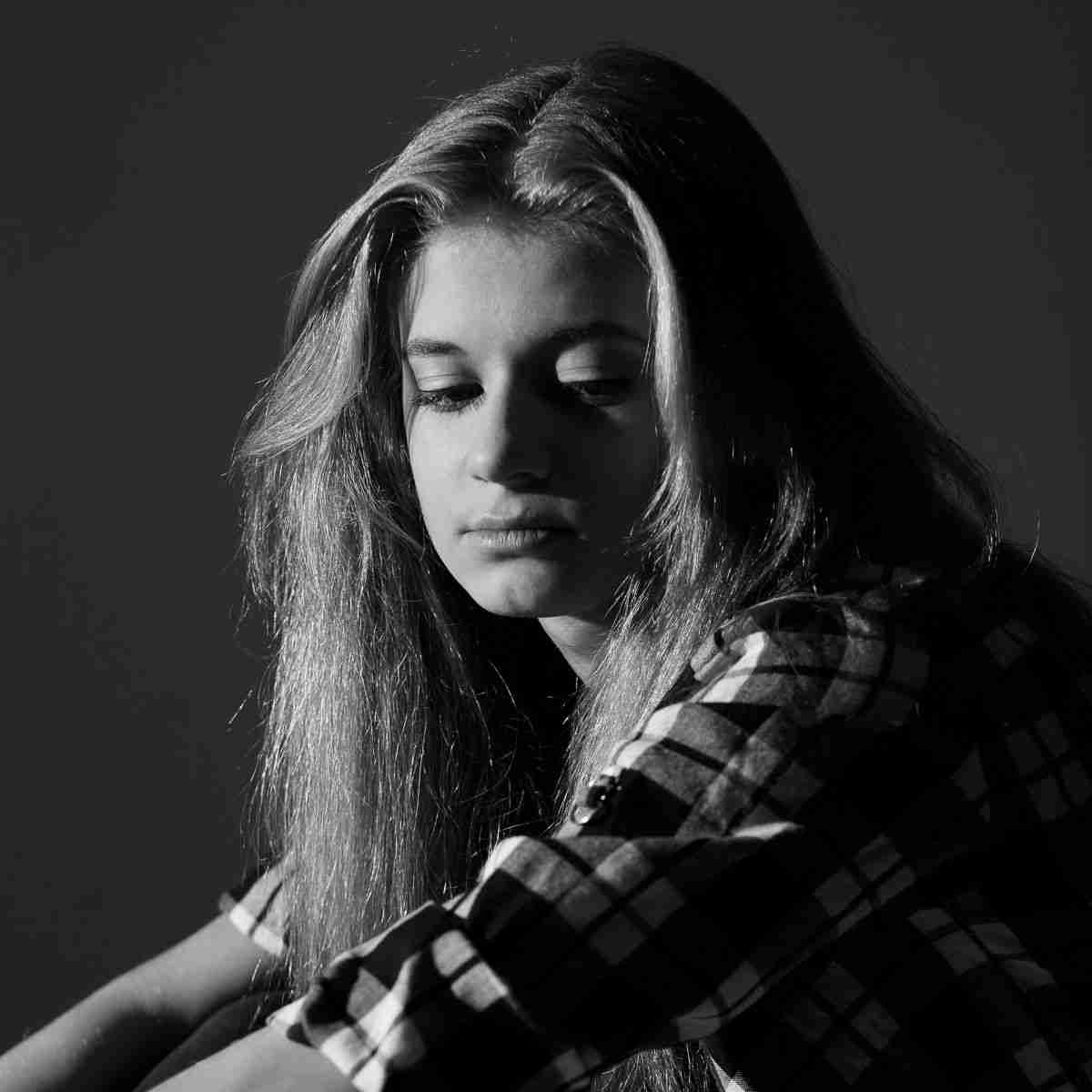 Img of young girl looking sad in a glommy room