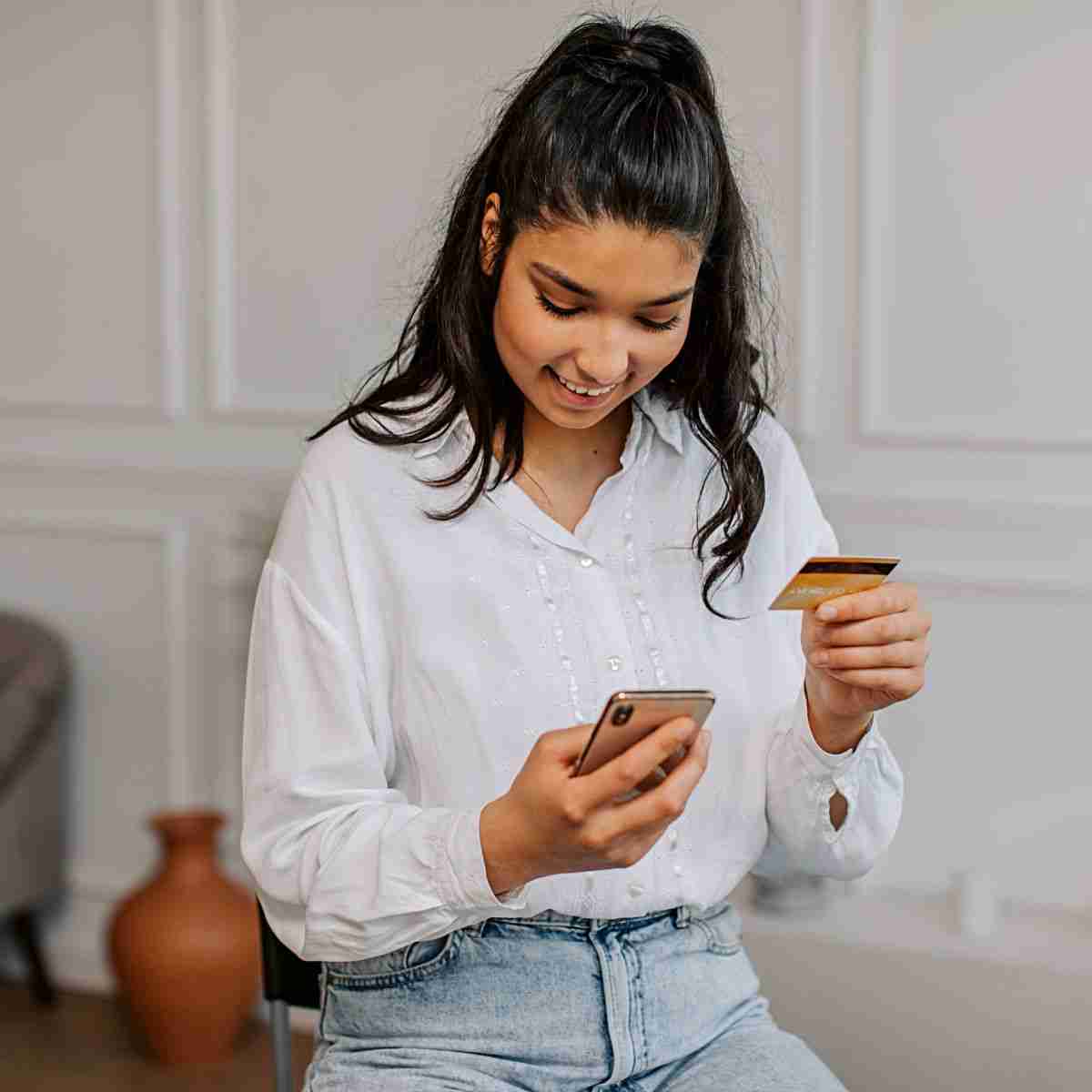 girl holding a credit card looking at her phone
